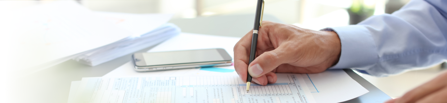 Hand with pen filling out tax forms | Gordon Delic